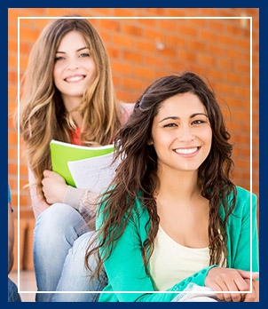 Two students sitting by the front of the school building